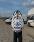 Person mit weißem Motocross-Helm, der das Allianz-Logo und den Namen "Robin Richter" trägt, vor einem Kiesparkplatz mit Transportern.