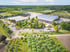 Luftaufnahme einer großen Baumschule mit mehreren Gebäuden, Parkplätzen und weitläufigen Baumreihen.