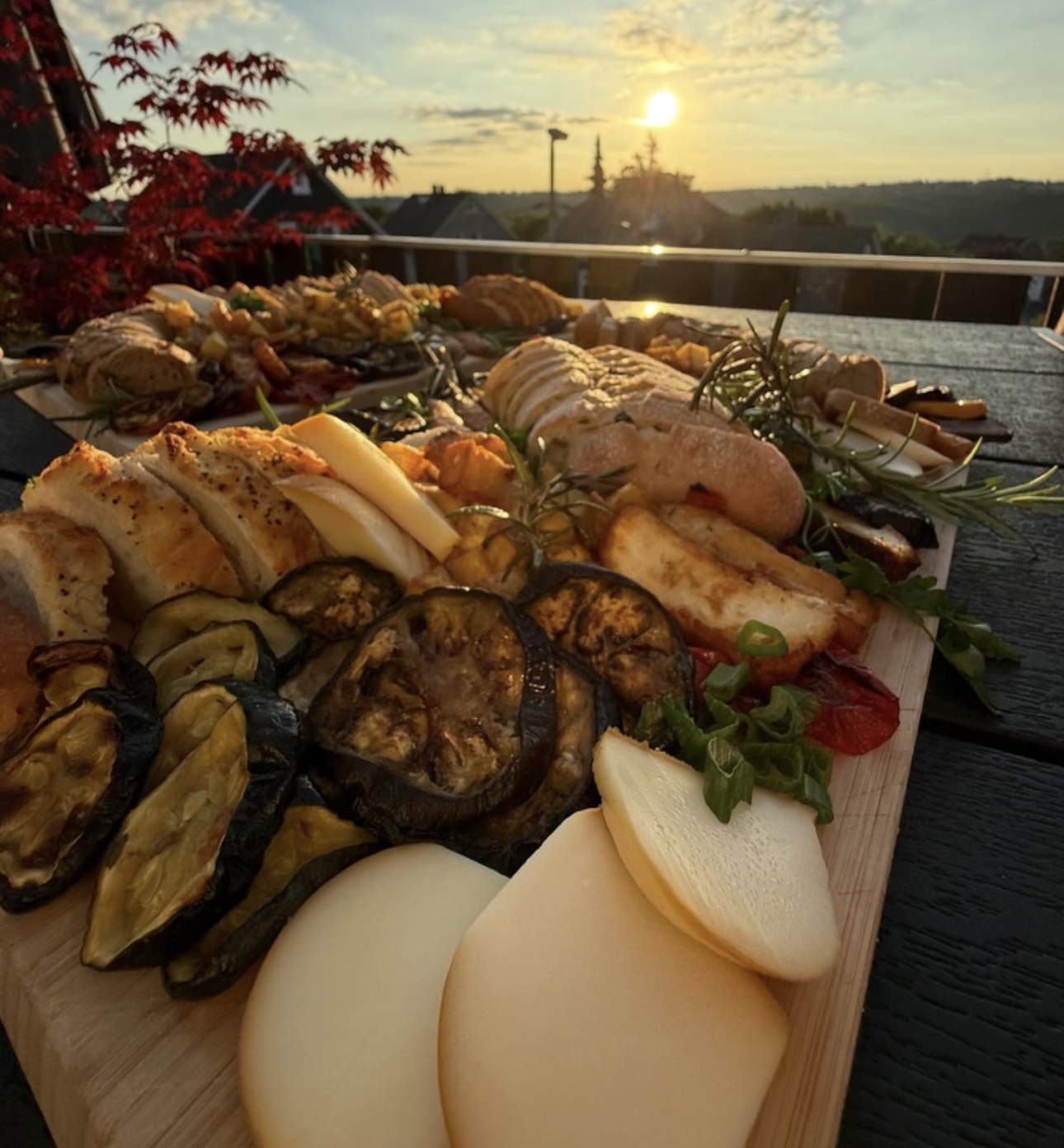 A grilled vegetable and cheese board on a terrace at sunset