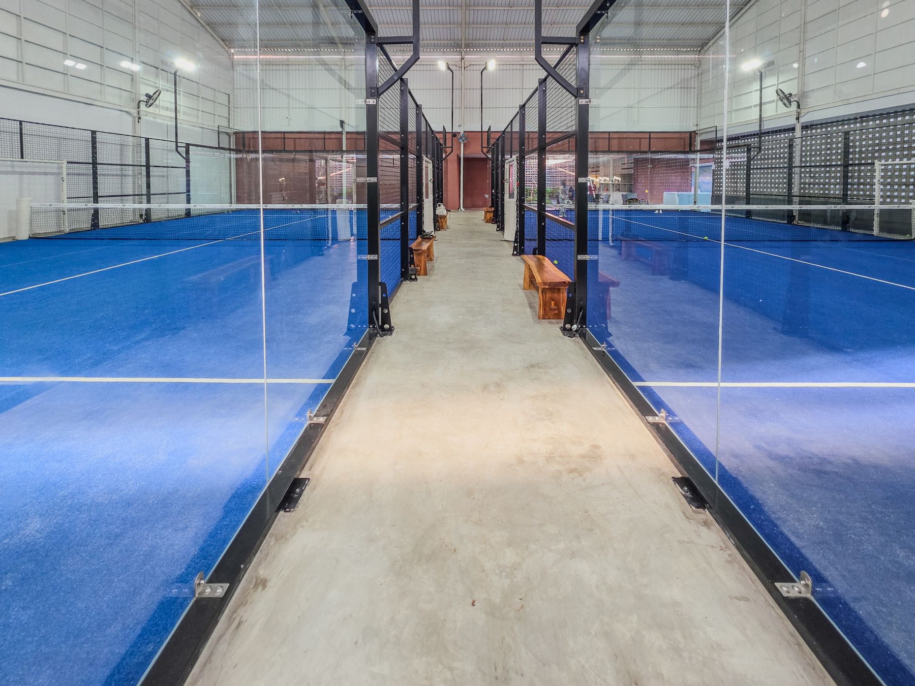 Padelhalle mit blauen Plätzen und Glaswänden