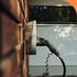 Eine Ladestation für Elektroautos ist an einer braunen Backsteinwand befestigt.