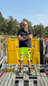 Mann mit Bart, Sonnenbrille und gelber Warnkleidung steht auf der Ladefläche eines gelben Abschleppwagens.