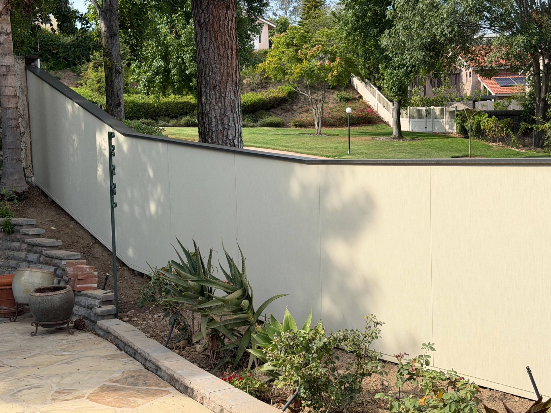 Hardie panel fence wall stepping down a landscaped slope in San Diego