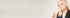 Blonde Frau im dunklen Blazer hält einen silbernen Stift vor hellem Hintergrund.