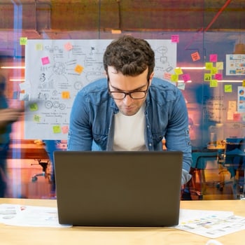 Titelbild zum kostenlosen Skript „Einstiege in IT-Präsentationen“: Mann arbeitet am Laptop vor Haftnotizen