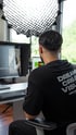Ein Mann bearbeitet ein Video an einem Computer; Text auf seinem Shirt: "DREAM CREATE VISUAL".