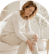 A woman sits on a sofa holding her knee with both hands while looking down with a pained expression.