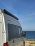 Nahaufnahme eines silbernen Campervans mit Aufschrift ‚REISEWAGEN SPORTIVE‘ – hochwertiger Ausbau für sportlich-aktives Vanlife mit Stil