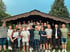 Eine Gruppe junger Erwachsener steht lächelnd vor einer Holzhütte.