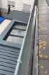 Dachrinne mit Wasser und graue Dachziegel, die teilweise mit gelbem Moos bedeckt sind, gereinigt durch Reinigungsfirma, Verstopfung gelöst.