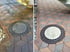 Vorher-Nachher-Vergleich einer gepflasterten Terrasse mit Kanaldeckel, von schmutzig und bewachsen zu sauber.