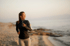 A smiling woman running on the beach with earbuds.