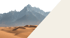 Sand dunes in a desert with snow-capped mountains in the background.