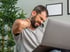 Man experiencing neck pain from muscle knots during work on laptop