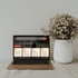 Ein goldener Laptop mit geöffneter Website-Startseite und einem weißen Blumenstrauß daneben.