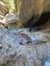 Eine Person seilt sich an einem Seil einen Wasserfall in einer felsigen Schlucht ab.