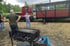 Ein Grill mit Kohle steht vor einer roten Lokomotive mit Personen und einem angehängten Güterwagen.