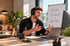 Lächelnder Mann mit Headset am Laptop neben Flipchart mit Text Leads, Gespräche, Erfolge im modernen Büro.