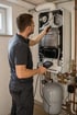 Heizungsbauer wartet eine geöffnete Gas-Brennwerttherme im Heizungskeller und misst die Abgaswerte