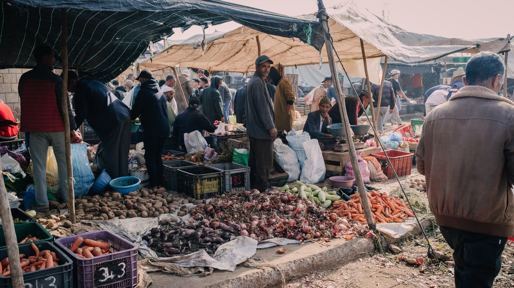 Gemüsestände unter Planen auf dem Wochenmarkt