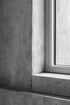 Graue Betonwand mit Fensterrahmen und Fensterbank aus hellem Granit.