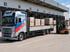Ein Gabelstapler belädt einen Volvo LKW von CW Transporte mit Paletten vor einer Lagerhalle mit Laderampen.