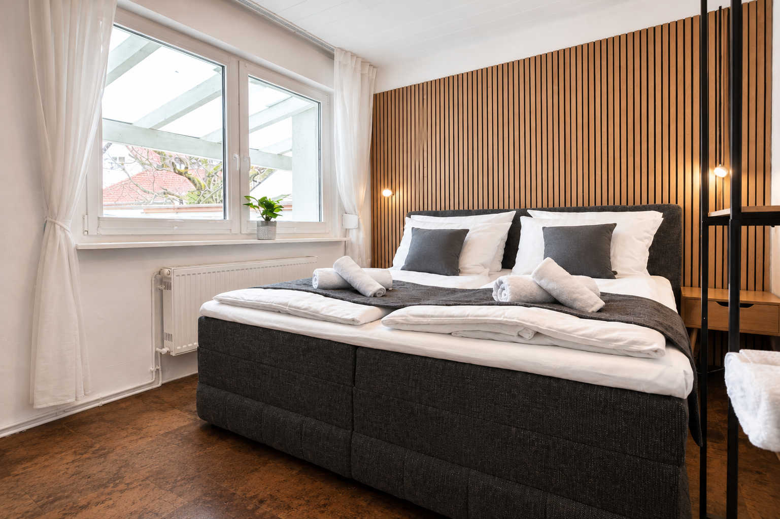 Schlafzimmer der Ferienwohnung in Großostheim mit Doppel-Boxspringbett und Holzlamellenwand