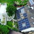Dach eines Hauses mit Solarmodulen, umgeben von Bäumen und Gärten.
