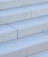 Close-up of light gray concrete stairs with a textured, non-slip surface and clean rectangular edges.