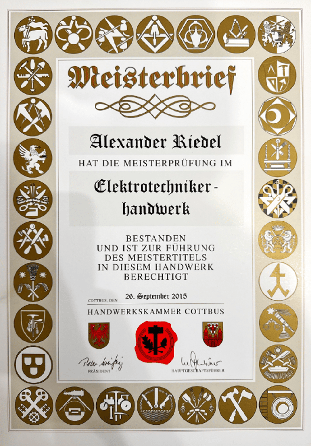 Meisterbrief von Alexander Riedel für Elektrotechniker-Handwerk, datiert 26. September 2015, umrahmt von Handwerkssymbolen.
