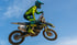 Ein Motocross-Fahrer in leuchtend gelb-schwarzer Ausrüstung springt auf einem Dirtbike mit der Nummer 188.