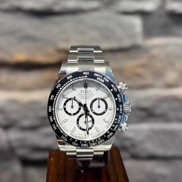 Eine Rolex Daytona Armbanduhr aus Edelstahl mit weißem Zifferblatt, drei schwarzen Hilfszifferblättern und schwarzer Tachymeter-Lünette.