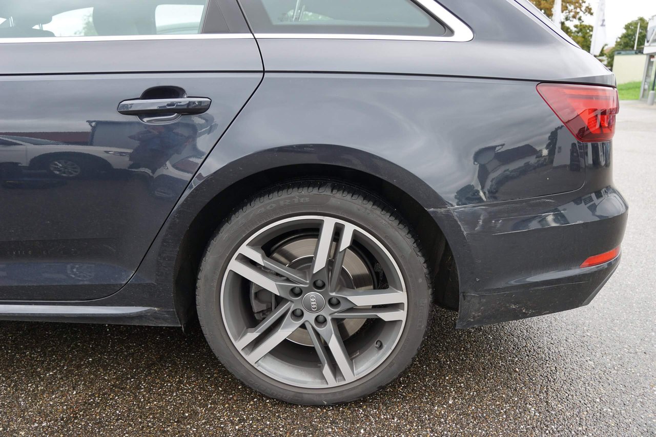 Hinterrad und Seitenteil eines dunkelgrauen Autos auf nasser Straße