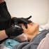 Eine Frau empfängt eine Gesichtsbehandlung mit einem Microneedling-Gerät.