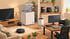 Ein Wohnzimmer mit Smart-Home-Geräten, darunter ein Fernseher, ein Gefrierschrank, eine Kaffeemaschine, ein Luftreiniger und ein Staubsaugerroboter.