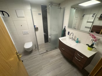 Badezimmer mit Waschplatz, WC und verglaster Dusche