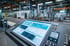 Industrieller Touchscreen-Monitor mit blauer Benutzeroberfläche in einer Fabrikhalle.