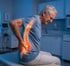 Older man sitting on an exam table, showing discomfort from a herniated disc.