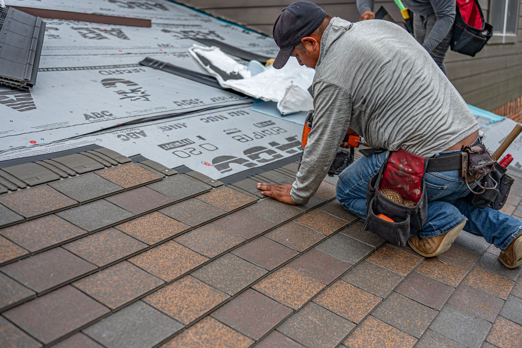 Roofer laying new shingle courses on a residential roof