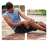 Man clutching his knee in pain while sitting on a brown track.