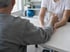 Ergotherapie nach Schlaganfall: Patient hebt eine Tasse, die Ergotherapeutin stützt den Unterarm – ErgoPlus Augsburg