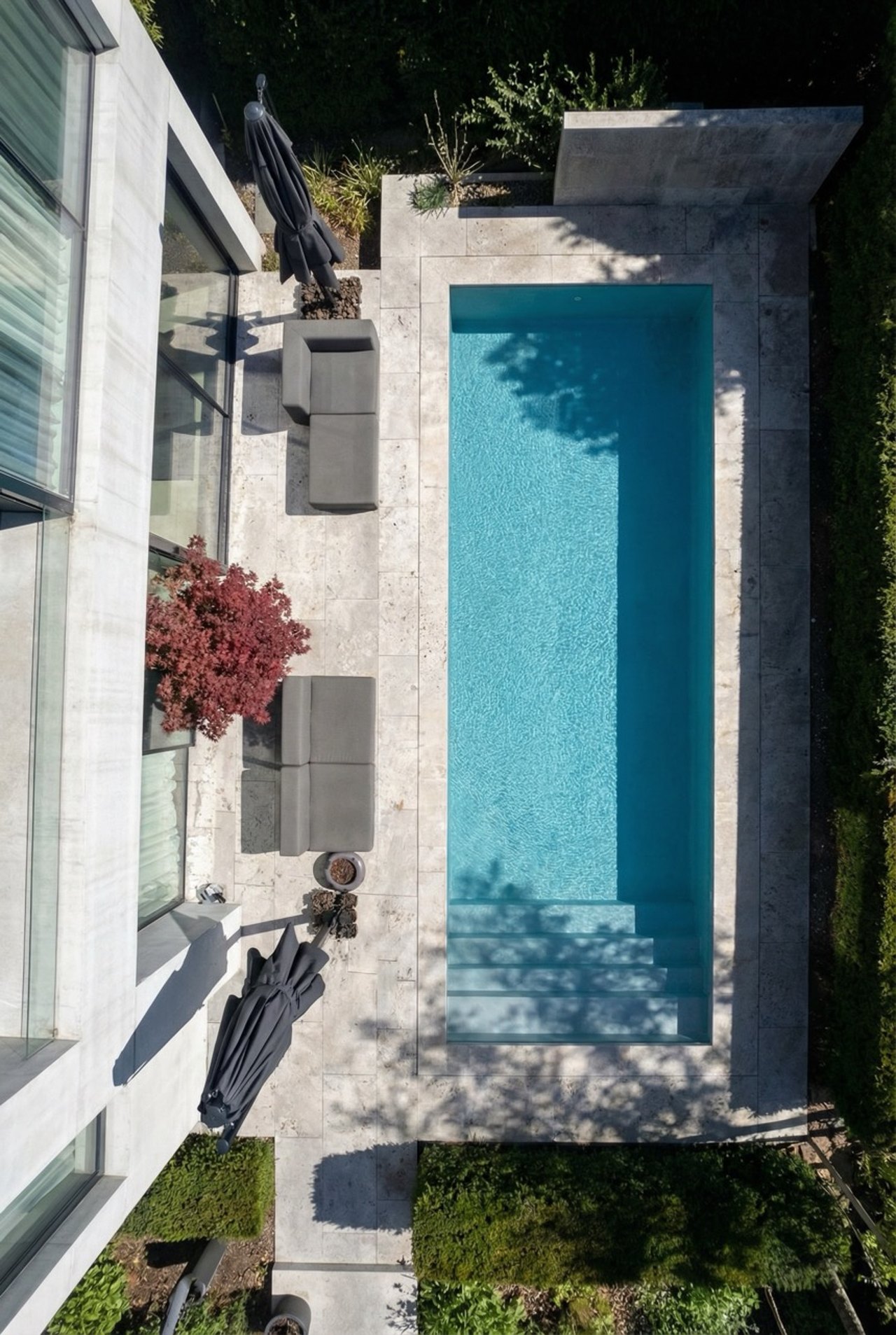 Pool mit blauen Fliesen, umgeben von Rasenfläche
