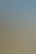 Eine lange Kolonnade mit Säulen und Skulpturen unter blauem Himmel, davor Gras und ein Weg.