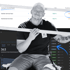 Mann in schwarzem Poloshirt und Jeans vor digitaler Anzeige mit Suchanfragen und Analysedaten.