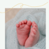Babyfüße liegen auf einer hellblauen, weichen Decke.
