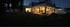 Modernes Haus bei Nacht mit hell erleuchteten Innenräumen und dunklem Garten.