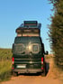Heckansicht eines grünen Campervans mit Solaranlage auf dem Aufstelldach – autarkes Reisemobil mit Solarstrom und Stauraum für Offroad- und Langzeitreisen