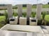 Moderner Gartenbrunnen aus Betonwürfeln mit Wasserschwall-Ausläufen vor hohen Sichtschutzelementen aus Beton und Gräsern.