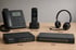 Tischtelefon, DECT-Telefon, Headset, Firewall und Switch sind auf einer Holzoberfläche nebeneinander angeordnet.