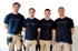 Vier Elektriker in blauen T-Shirts mit dem Logo „Das ElektroWerk“ und beigefarbenen Arbeitshosen.